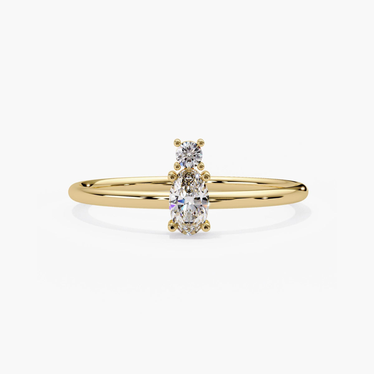 Oval and round two stone diamond ring in 14k yellow gold, with one oval lab grown diamond beside a smaller round on a dainty band.