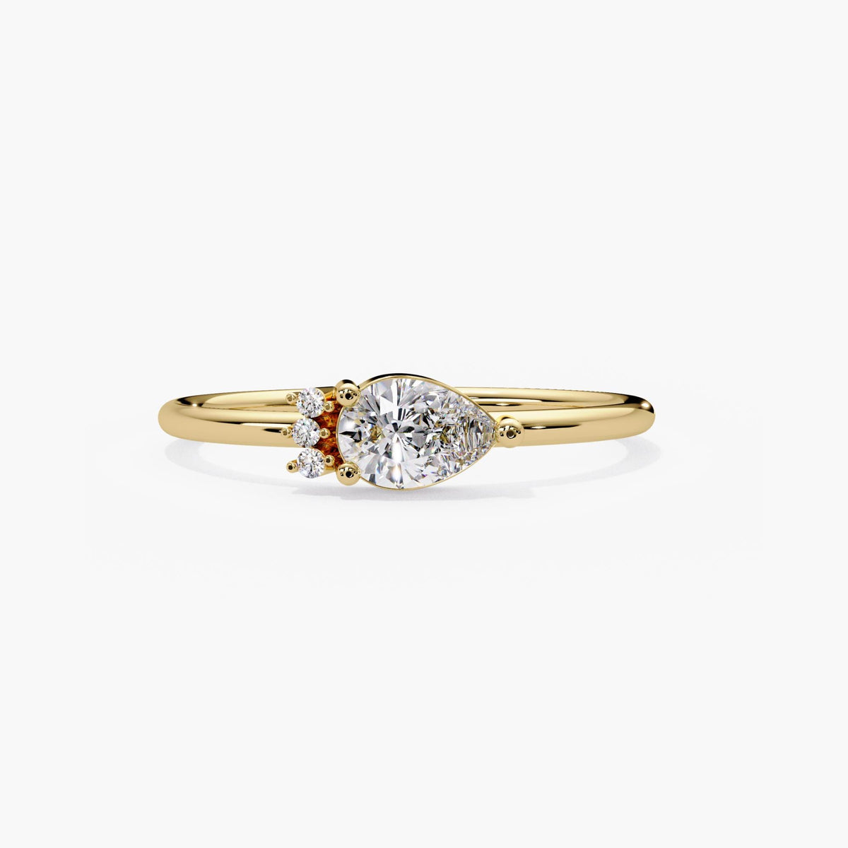 East west pear diamond ring in 14k yellow gold, with a pear lab grown diamond set horizontally beside a cluster of three small round diamonds.