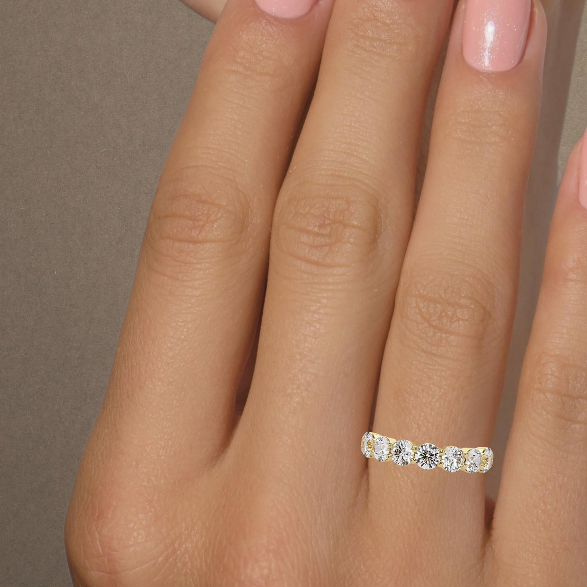 Round diamond wedding band worn on a finger, 4 mm lab grown diamonds and yellow gold band.