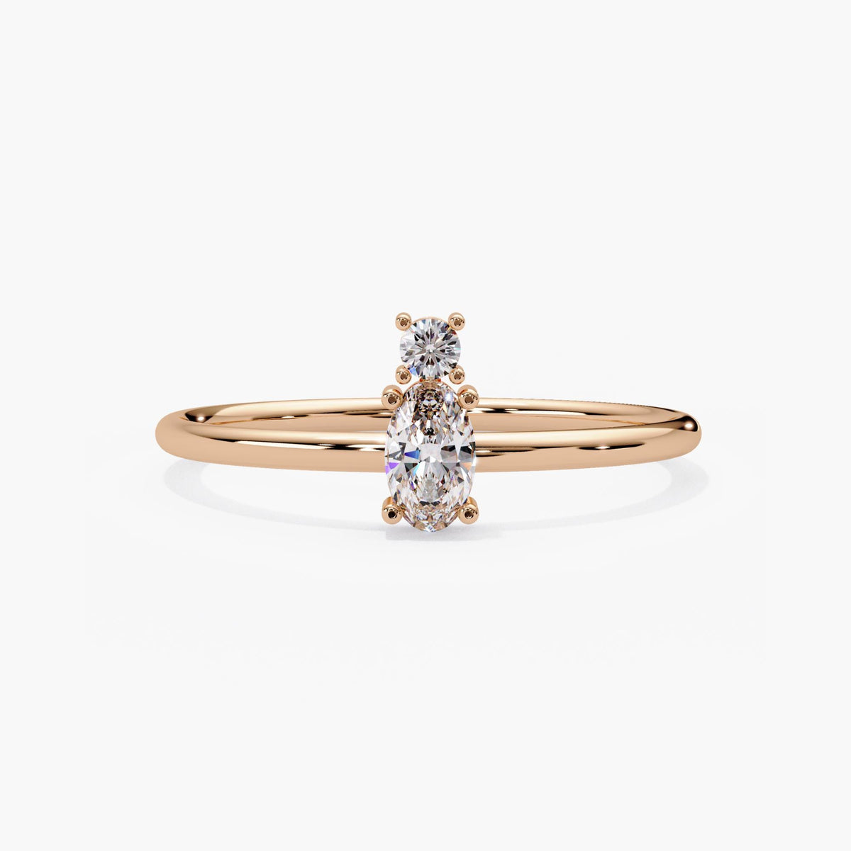 14k rose gold two stone diamond ring with an oval lab grown diamond and a smaller round on a dainty band.