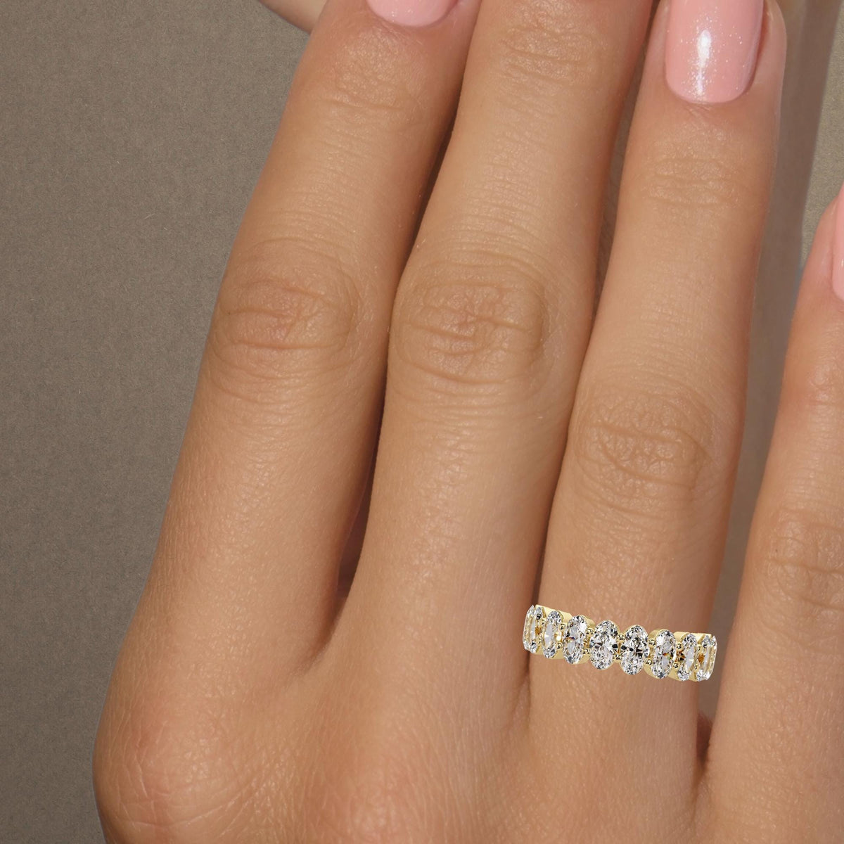 Oval lab grown diamond half eternity band worn on a finger, showing the scale of the 5x3 mm diamonds and yellow gold setting.