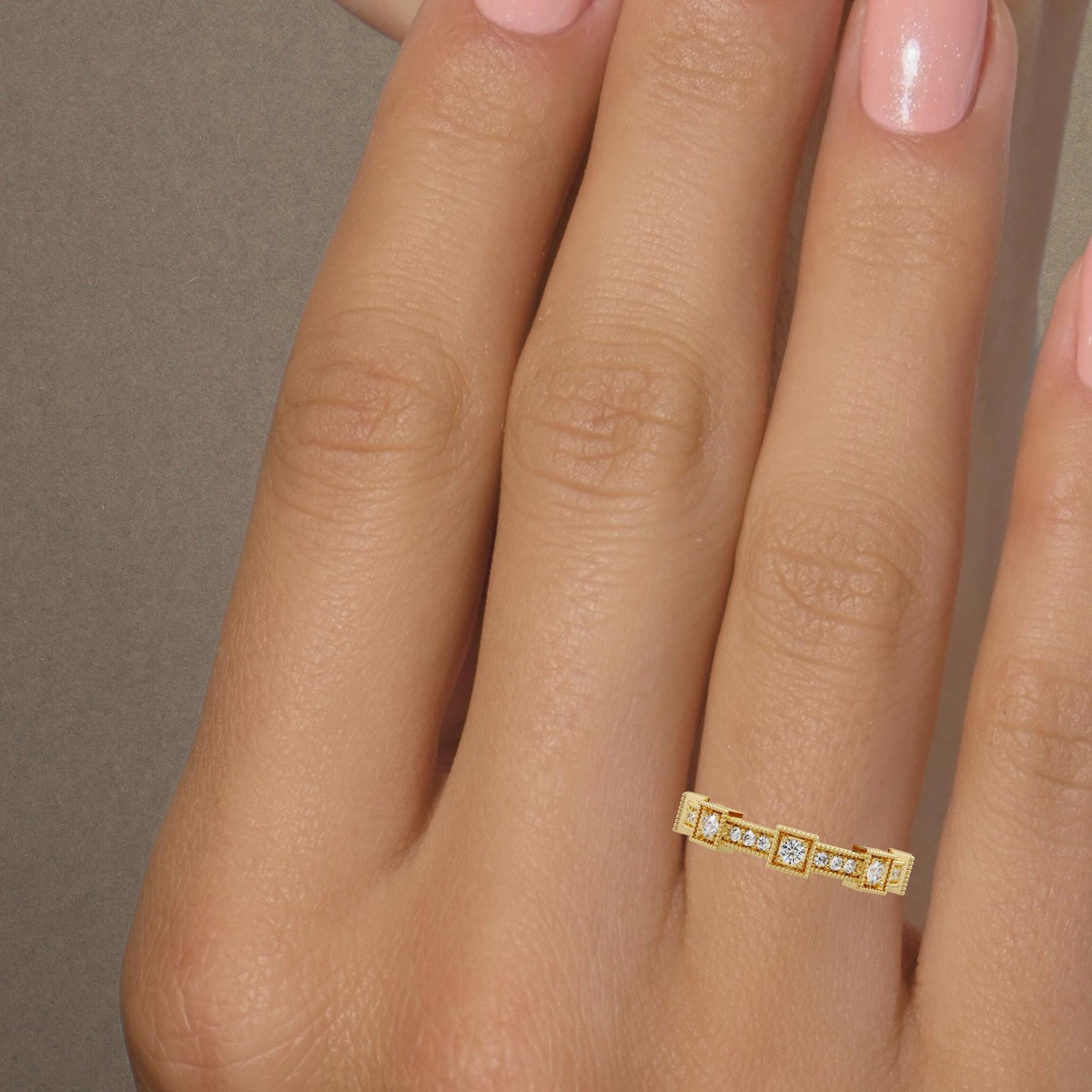 A single vintage-inspired lab diamond eternity band worn on a hand, showing its slim yellow gold profile, geometric diamond pattern and delicate beaded edges.